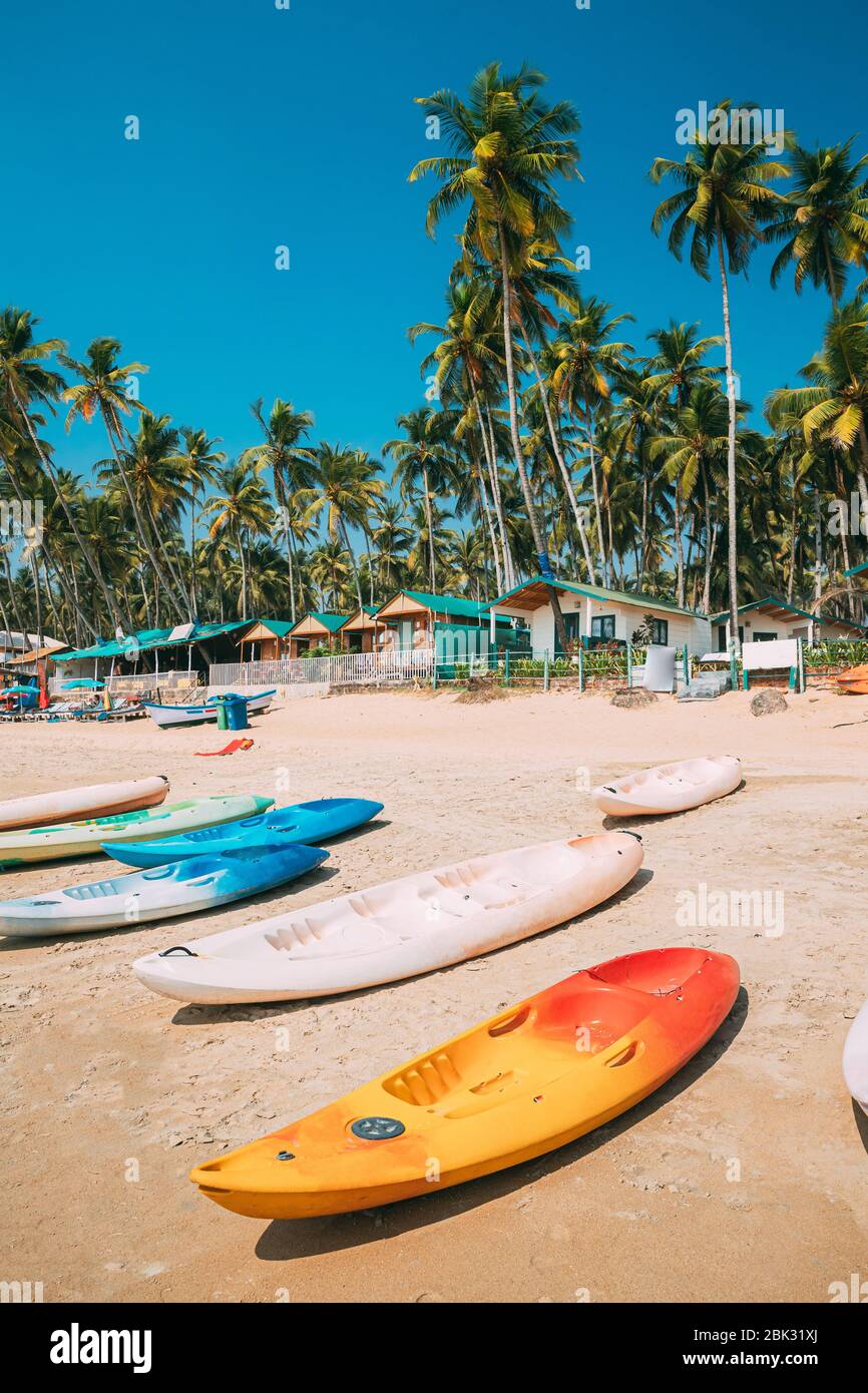 Canacona, Goa, Inde. Canoë kayak à louer stationné sur la célèbre plage de Palolem sur fond Grand arbre de palmiers en été Sunny Day. Banque D'Images