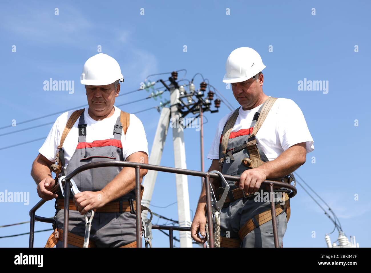 Deux ouvriers en électricité sur un ascenseur. Les ingénieurs se montent sur une grue pour réparer un support de grande hauteur. Les hommes éliminent l'accident à la station haute altitude Banque D'Images