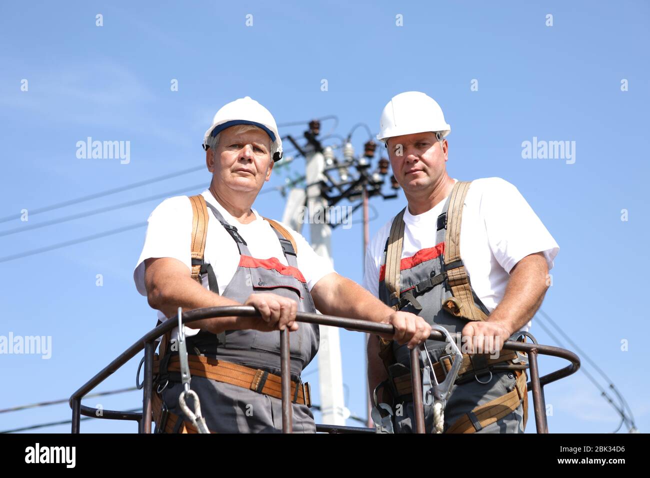 Deux ouvriers en électricité sur un ascenseur. Les ingénieurs se montent sur une grue pour réparer un support de grande hauteur. Les hommes éliminent l'accident à la station haute altitude Banque D'Images