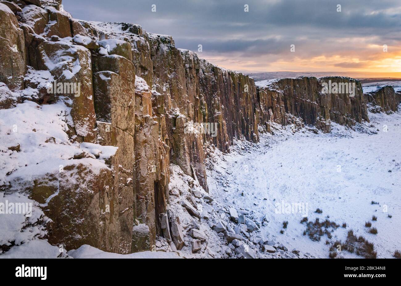 Coucher de soleil d'hiver sur un paysage couvert de neige sombre à Walltown Crags partie du sentier longue distance du mur d'Hadrien dans le parc national de Northumberland Banque D'Images