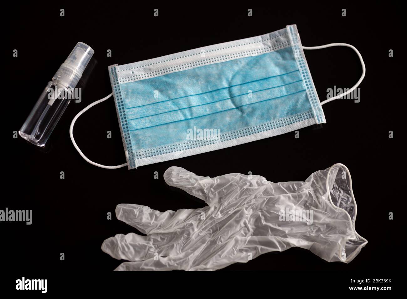 Un masque chirurgical, des gants et de l'alcool pendant la quarantaine du coronavirus covid-19. Arrière-plan noir Banque D'Images