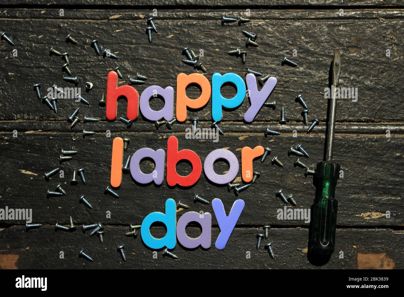Texte Happy Labor Day en plusieurs couleurs sur fond de bois avec outils de réparation de construction. Signe de concept de la journée de travail. Banque D'Images
