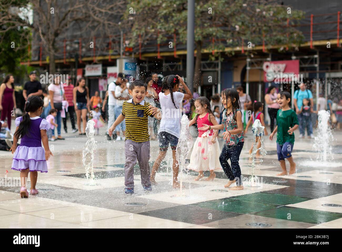 Enfants jouant dans une fontaine d'eau sur une place principale à San Jose, Costa Rica Banque D'Images
