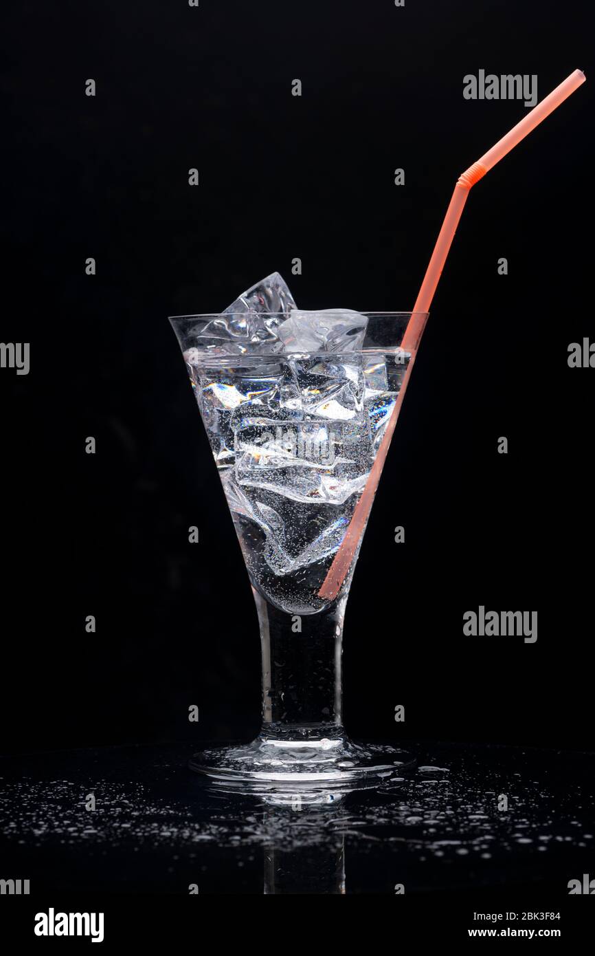 Verre à boire transparent avec de la glace et une paille en plastique orange. Banque D'Images