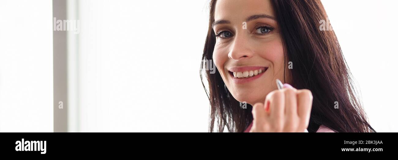Une fille de travailleur de bureau tenant le visage du stylo et souriant Banque D'Images