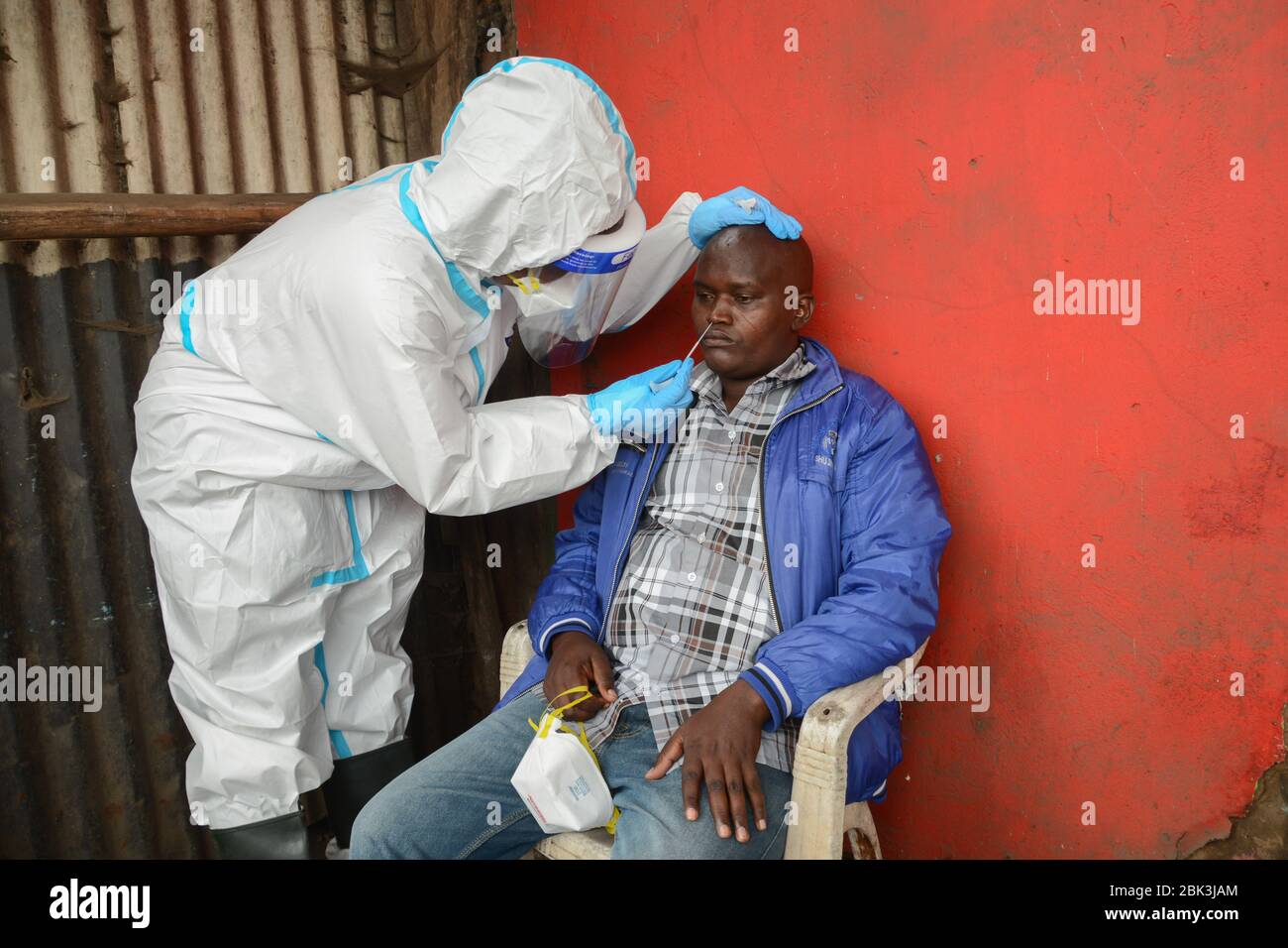 Un agent de santé effectue un test de prélèvement sur un résident pendant la pandémie du virus corona. Un test de masse des cas COVID-19 dans la région de Kawangware a été effectué sur les résidents. Jusqu'à présent, le Kenya a signalé 411 cas de coronavirus, 144 reprises et 17 décès. Banque D'Images