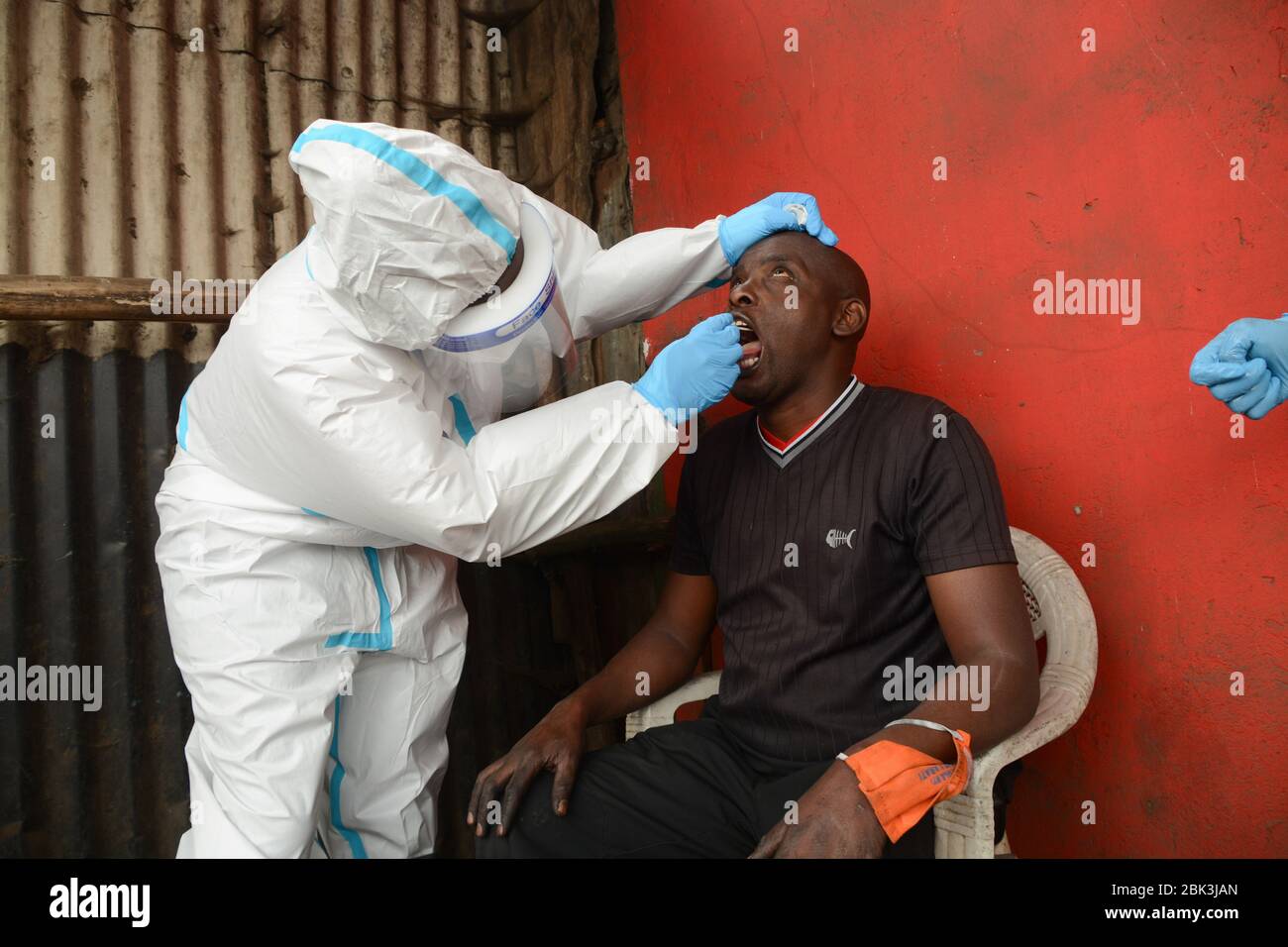 Un agent de santé effectue un test de bouche-à-oreille sur un résident pendant la pandémie du virus corona. Un test de masse des cas COVID-19 dans la région de Kawangware a été effectué sur les résidents. Jusqu'à présent, le Kenya a signalé 411 cas de coronavirus, 144 reprises et 17 décès. Banque D'Images