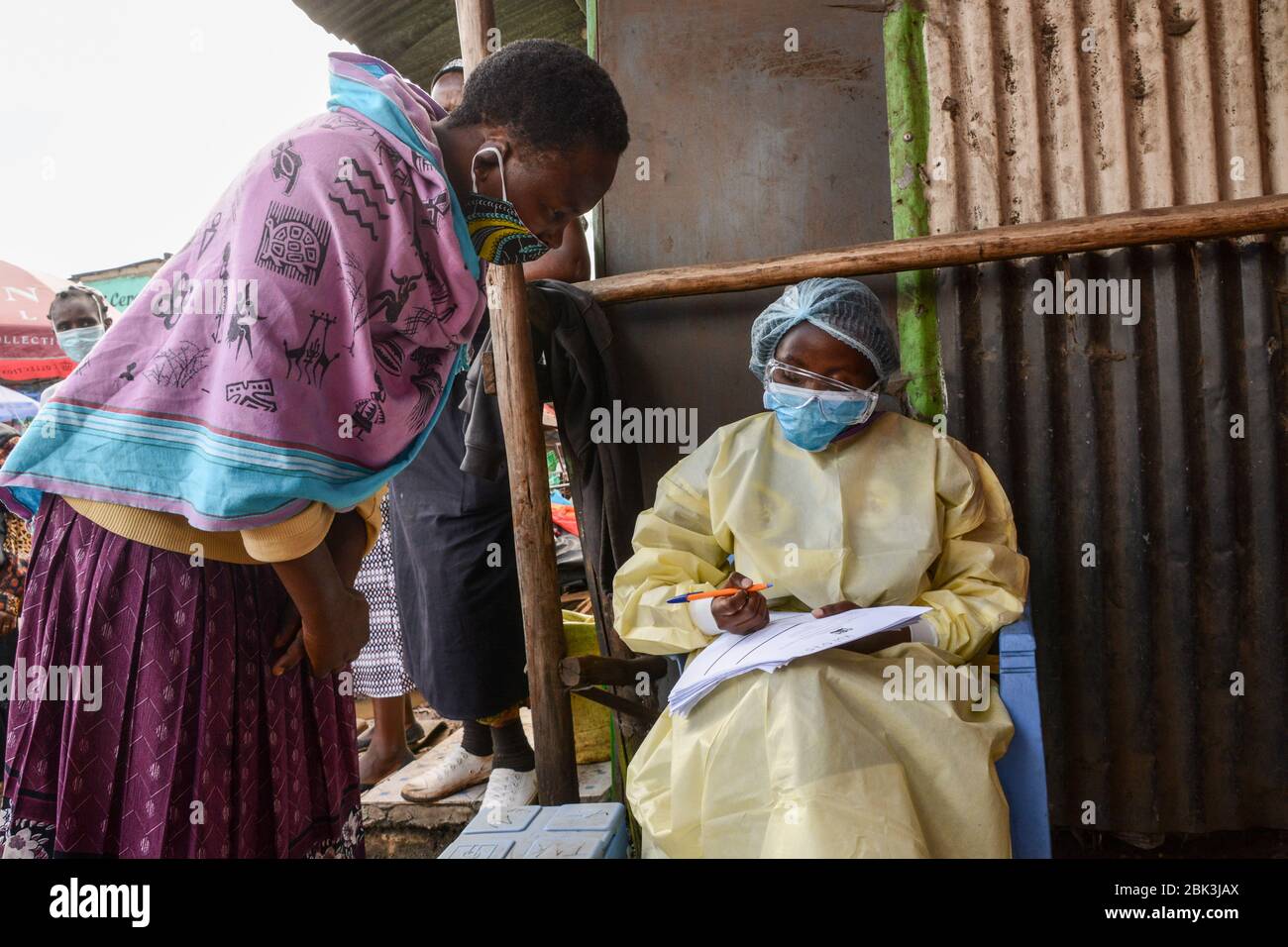 Un professionnel de la santé en équipement de protection par mesure de précaution recueille les détails d'un résident pendant la pandémie du virus corona. Un test de masse des cas COVID-19 dans la région de Kawangware a été effectué sur les résidents. Jusqu'à présent, le Kenya a signalé 411 cas de coronavirus, 144 reprises et 17 décès. Banque D'Images
