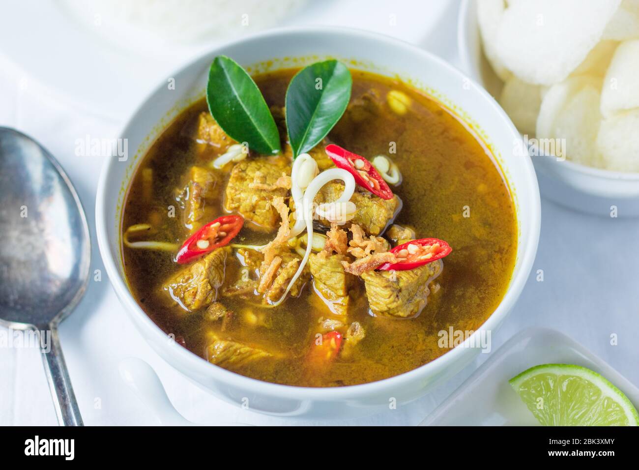 Rawon est une soupe traditionnelle noire de bœuf indonésien. Servi avec du riz à la vapeur, de l'oeuf salé, des pousses de haricots, des sambal et du krupuk (crackers de crevettes) Banque D'Images