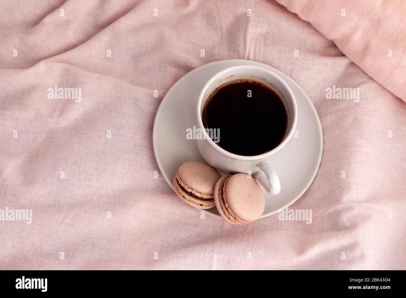 Un verre le matin avec des macarons au lit. Petit déjeuner romantique et lettre, vue sur le dessus. Banque D'Images