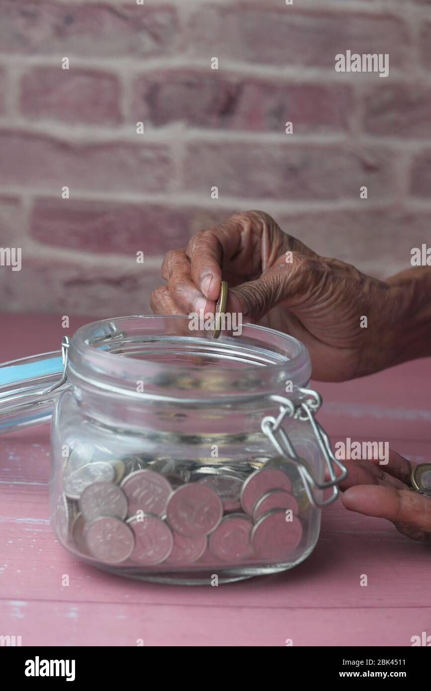 Les femmes âgées économisent des pièces dans un pot. Banque D'Images