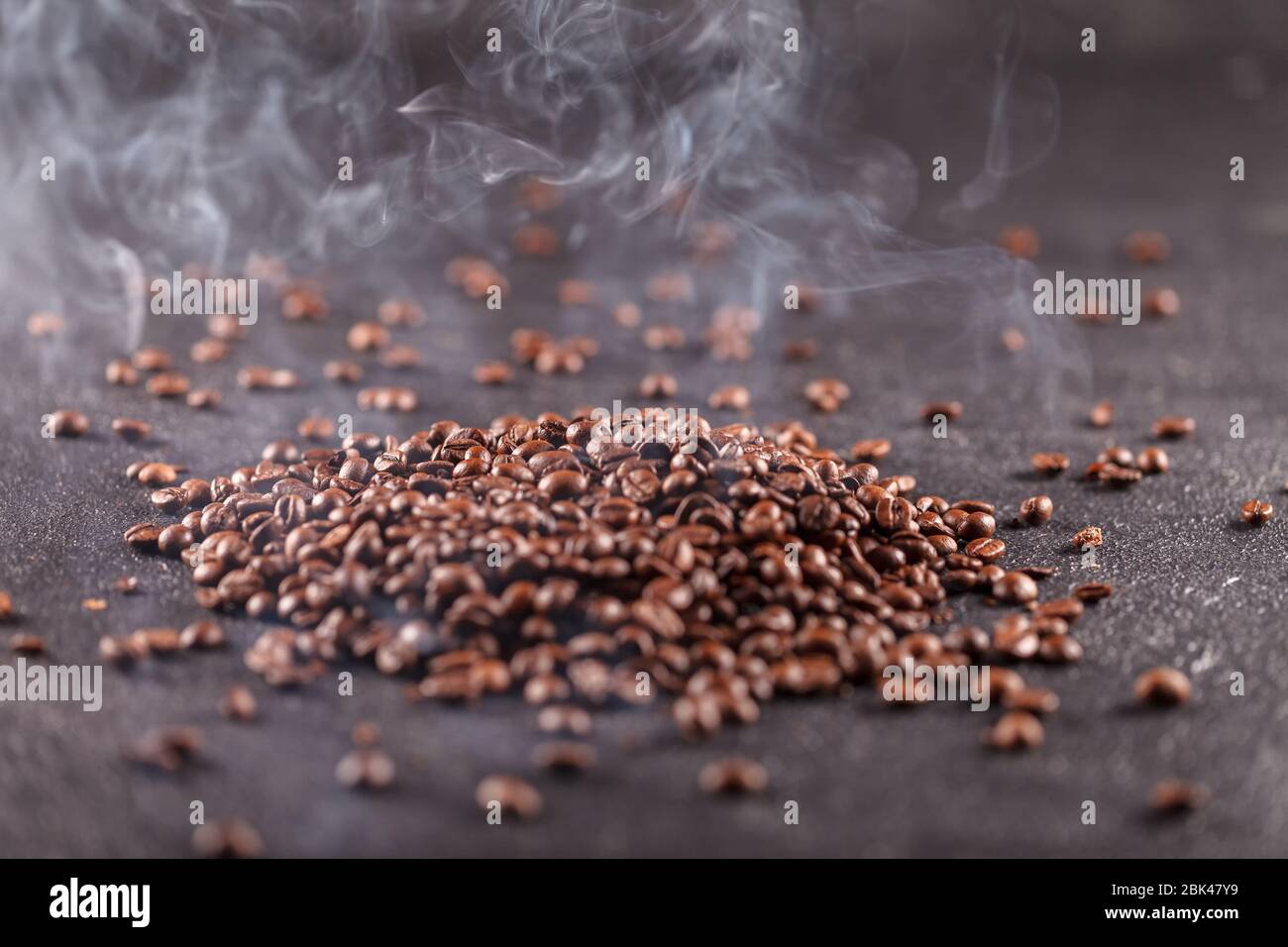 Les grains de café aromatiques fraîchement torréfiés se trouvent sur une surface sombre. Concept de boisson fraîche parfumée le matin Banque D'Images