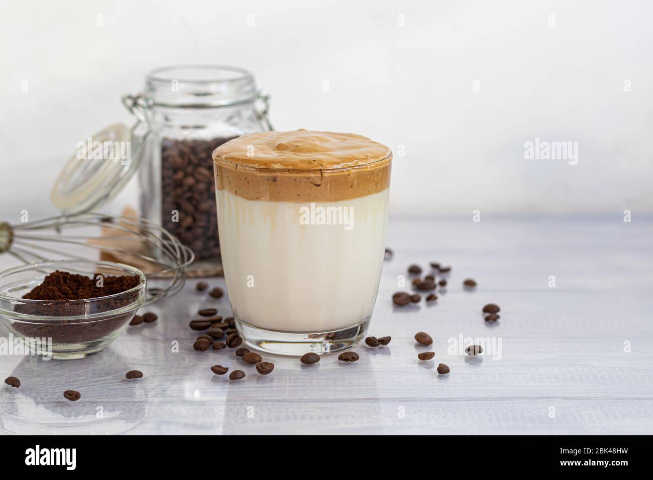 Le café Dalgona est une boisson froide et tendance de la Corée. Café savoureux et aromatique avec lait et sucre dans un verre sur fond blanc. Espace de copie Banque D'Images