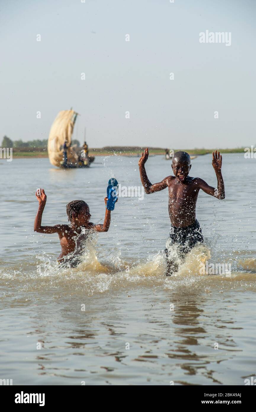Un garçon et une fille jouent et éclabousse dans l'eau de la rivière Bani à Mopti au Mali, en Afrique de l'Ouest. Banque D'Images
