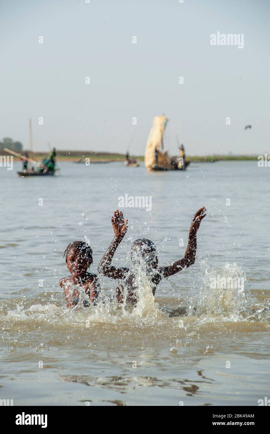 Un garçon et une fille jouent et éclabousse dans l'eau de la rivière Bani à Mopti au Mali, en Afrique de l'Ouest. Banque D'Images