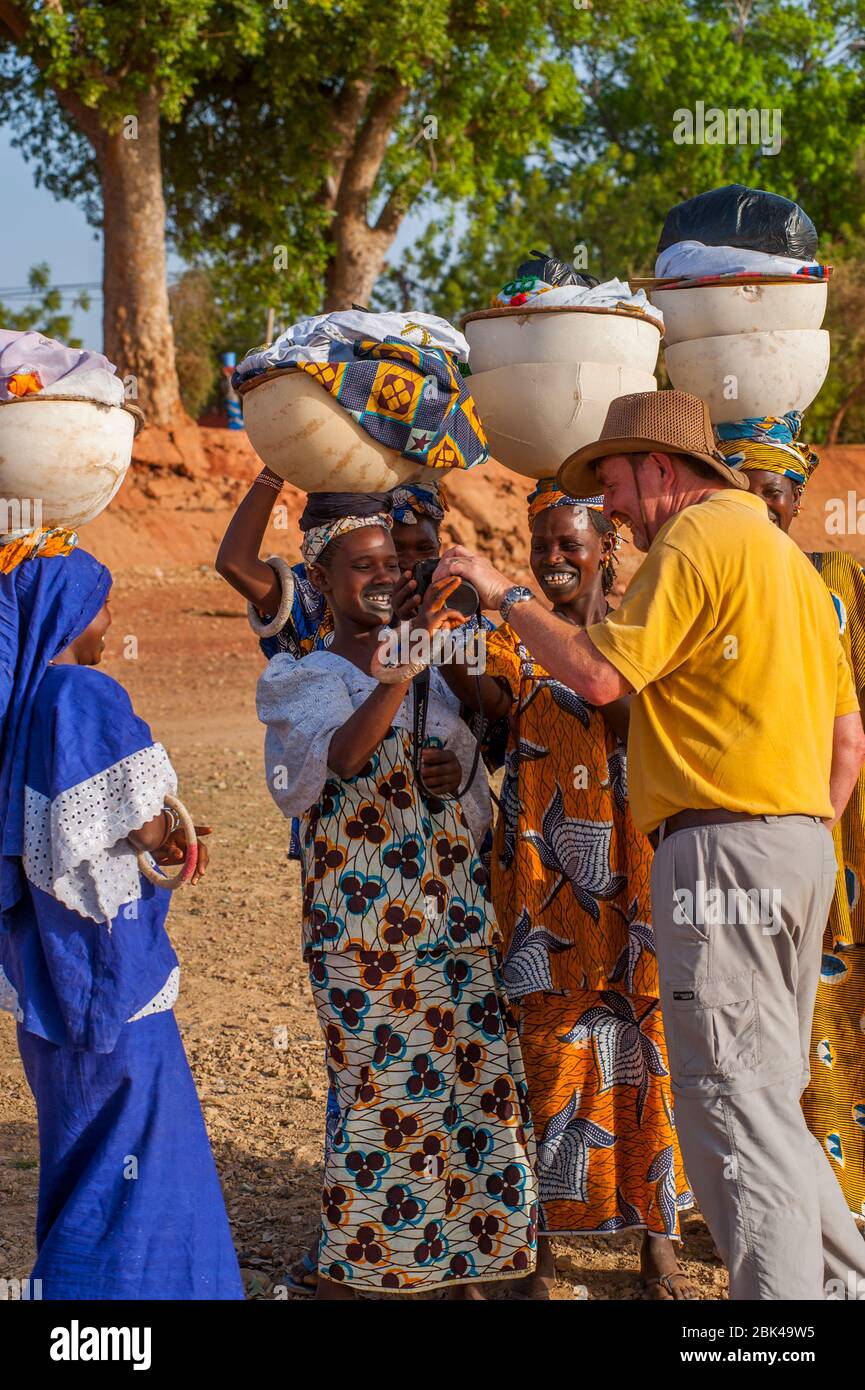 Un touriste montre une photo numérique aux femmes locales portant la lessive sur leur tête sur le rivage de la rivière Bani à Mopti au Mali, en Afrique de l'Ouest. Banque D'Images