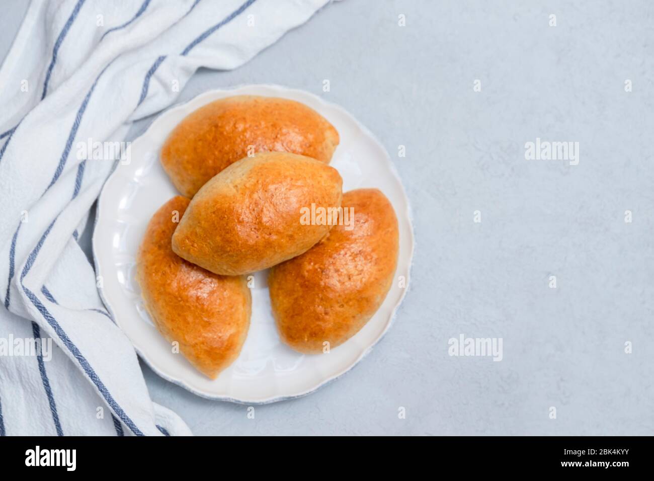Pirozhki (petits pains farcis) sur plaque blanche sur fond en béton neutre. Vue de dessus, espace de copie Banque D'Images