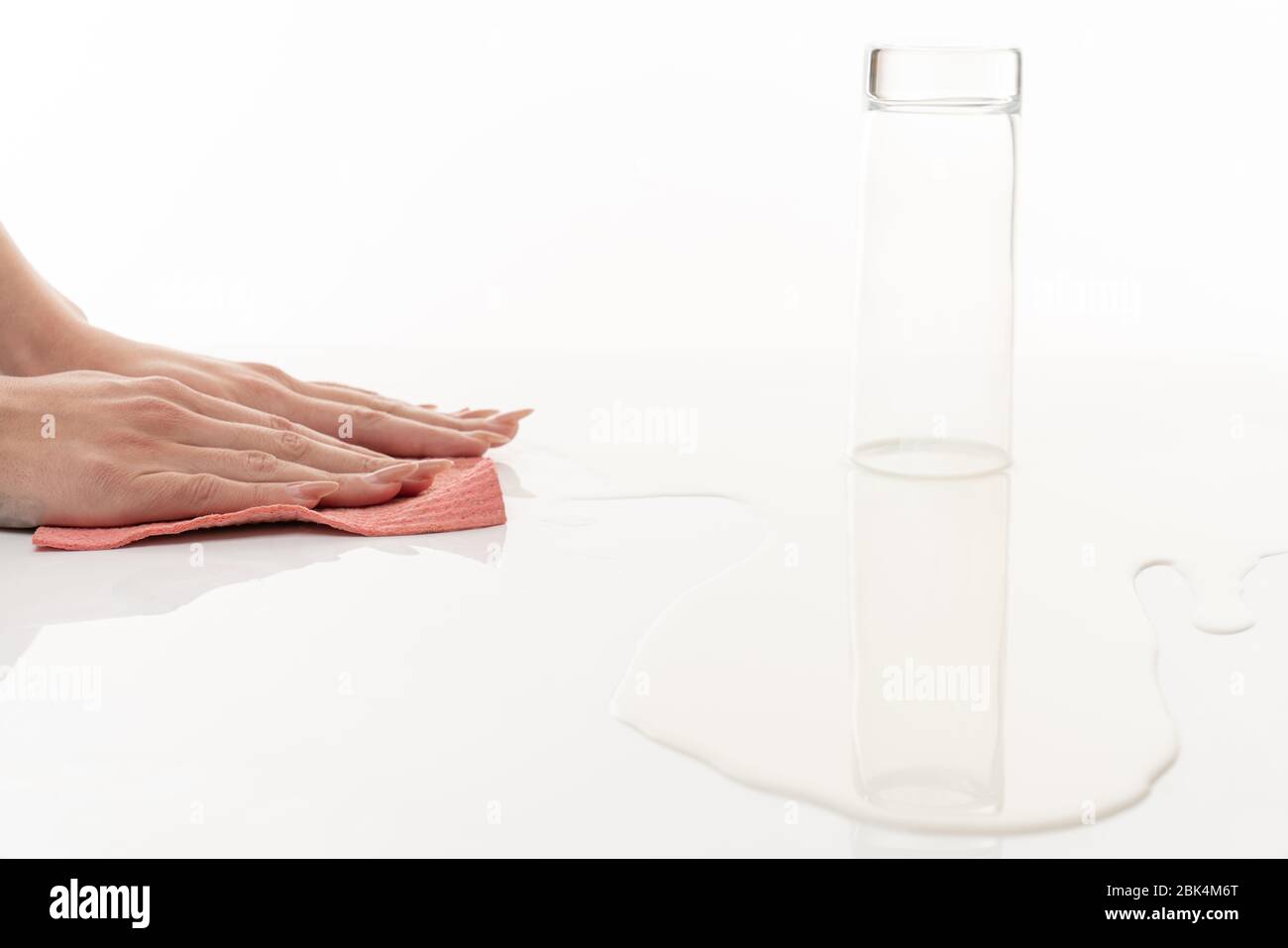 Les mains féminines essuie le lait renversé avec un chiffon Banque D'Images Les mains féminines essuie le lait renversé avec un chiffon Banque D'Images