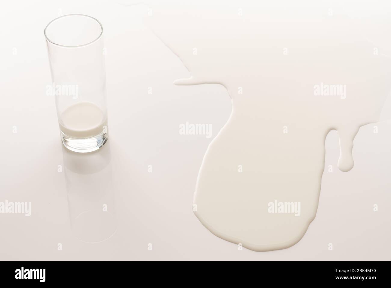 Lait au fond d'un verre et lait renversé sur le blanc Banque D'Images Lait au fond d'un verre et lait renversé sur le blanc Banque D'Images