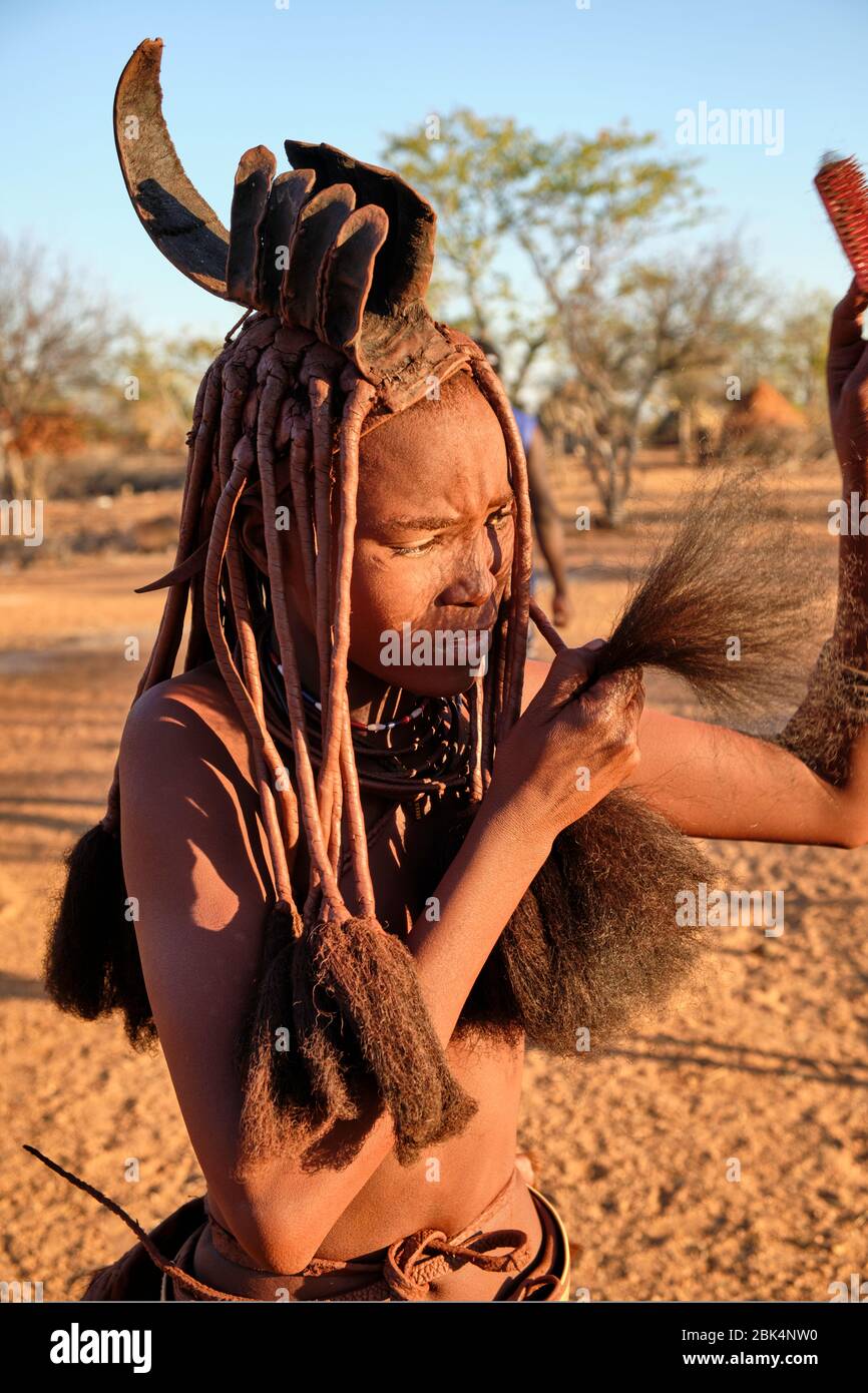 Batwa fille dans la robe traditionnelle combater ses cheveux au coucher du soleil. Banque D'Images