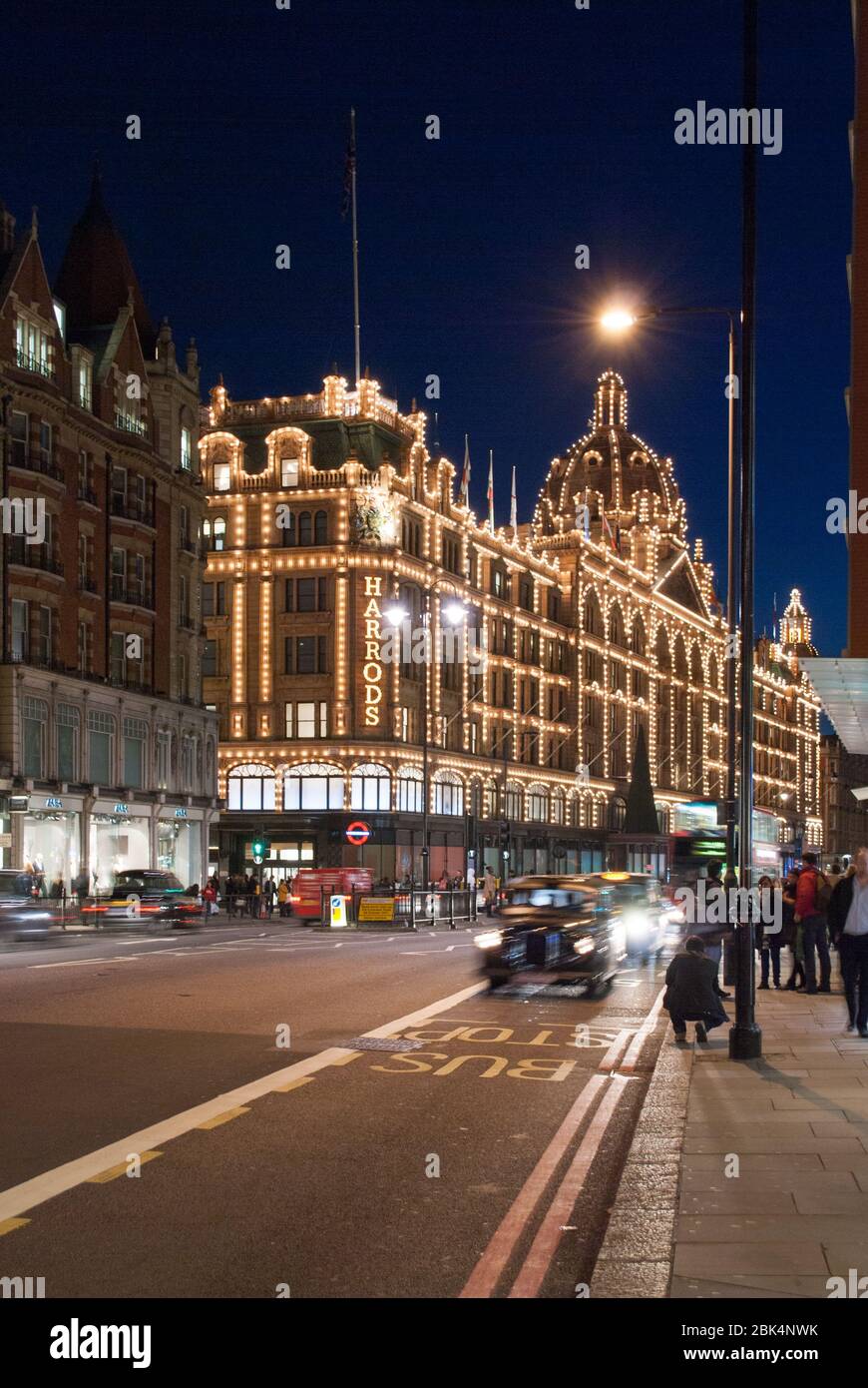 Nuit lumières foncées élévation éclairée avant Knightsbridge Harrods, 87–135 Brompton Road, Londres, Angleterre W3 par Charles William Stephens Banque D'Images