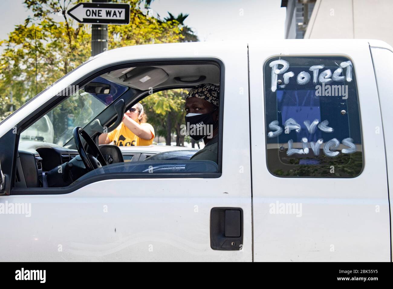 Homme conduisant un véhicule portant un masque facial avec une affiche tracée sur la fenêtre pendant l'éclosion du coronavirus Banque D'Images