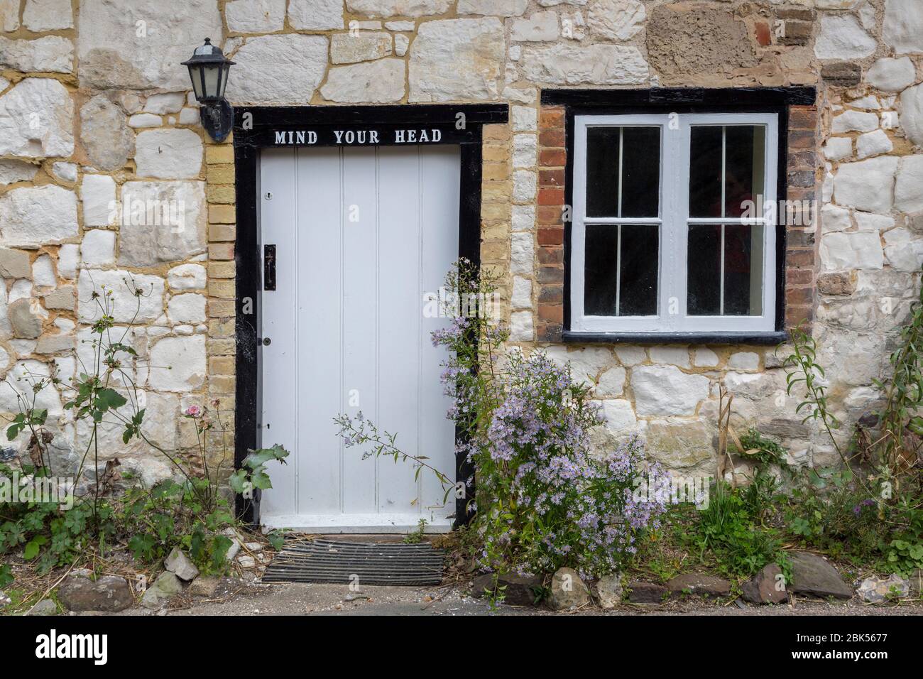 Porte de cottage en pierre avec votre panneau tête, Brightstone, Isle of Wight, Angleterre, Royaume-Uni Banque D'Images