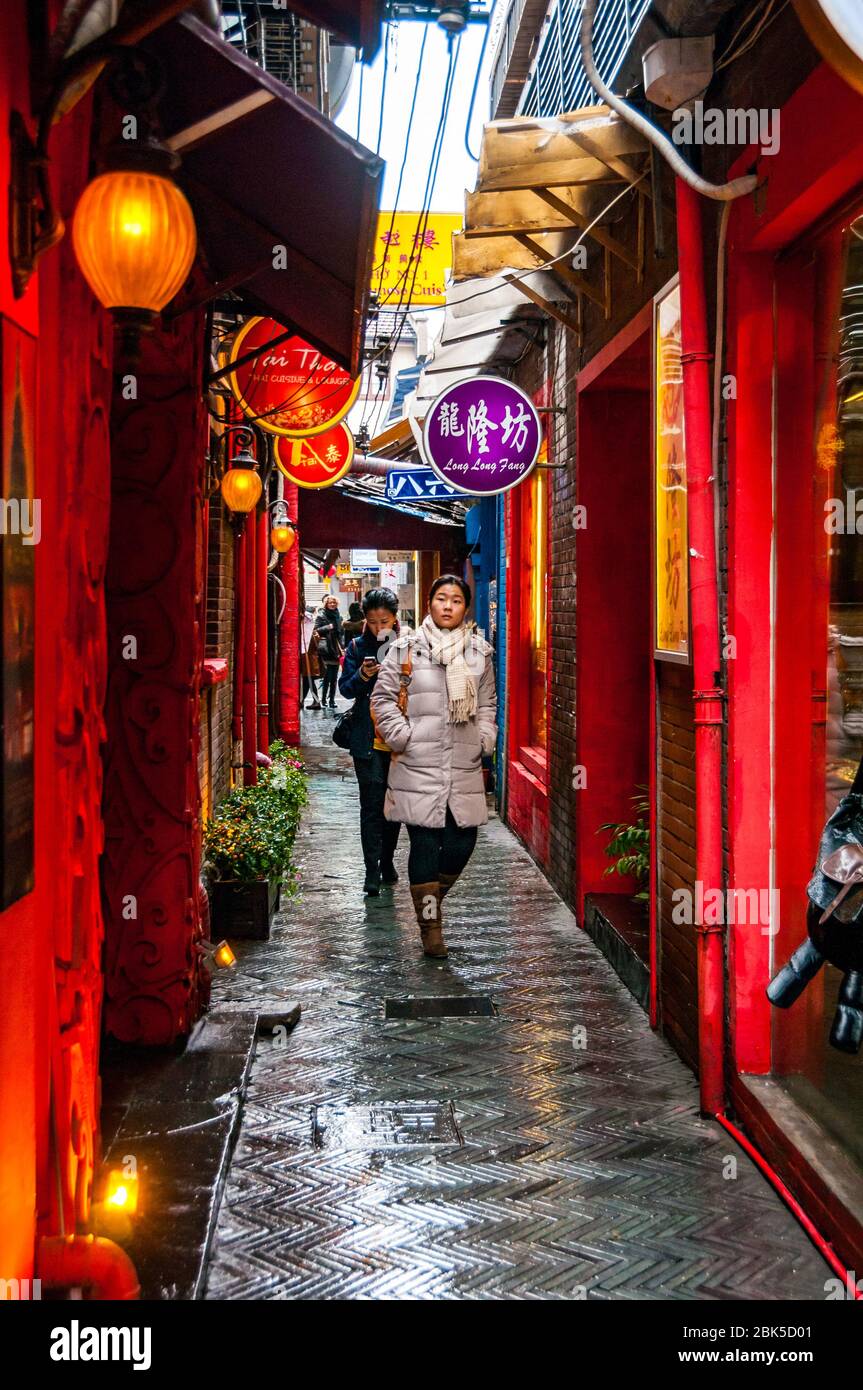 Une jeune femme chinoise marche dans une ruelle à Tianzifang par temps humide. Shanghai, Chine. Banque D'Images