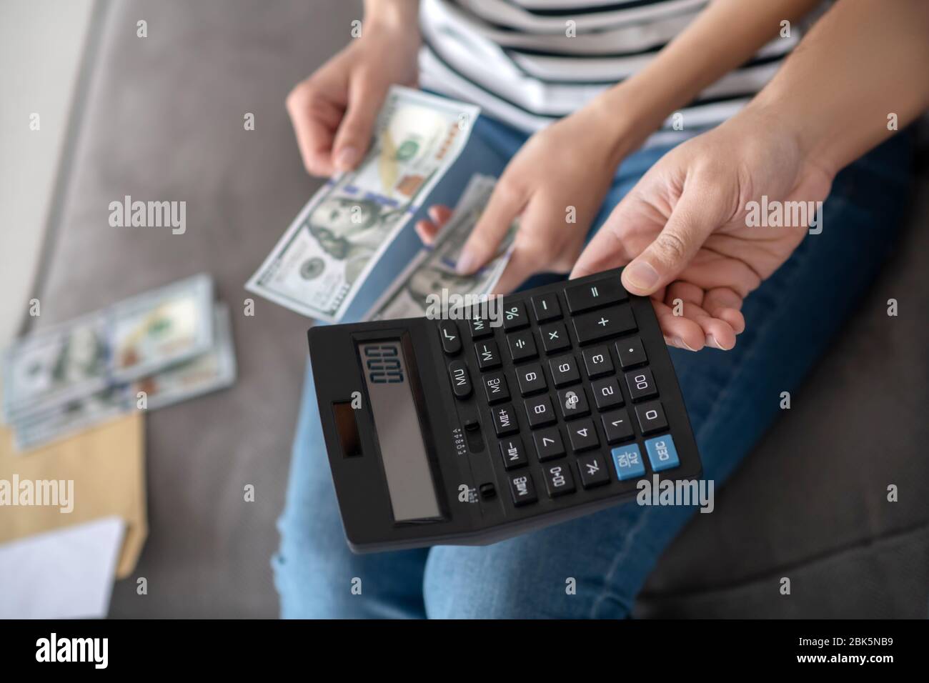 Main masculine avec une calculatrice mains femelles avec de l'argent. Banque D'Images