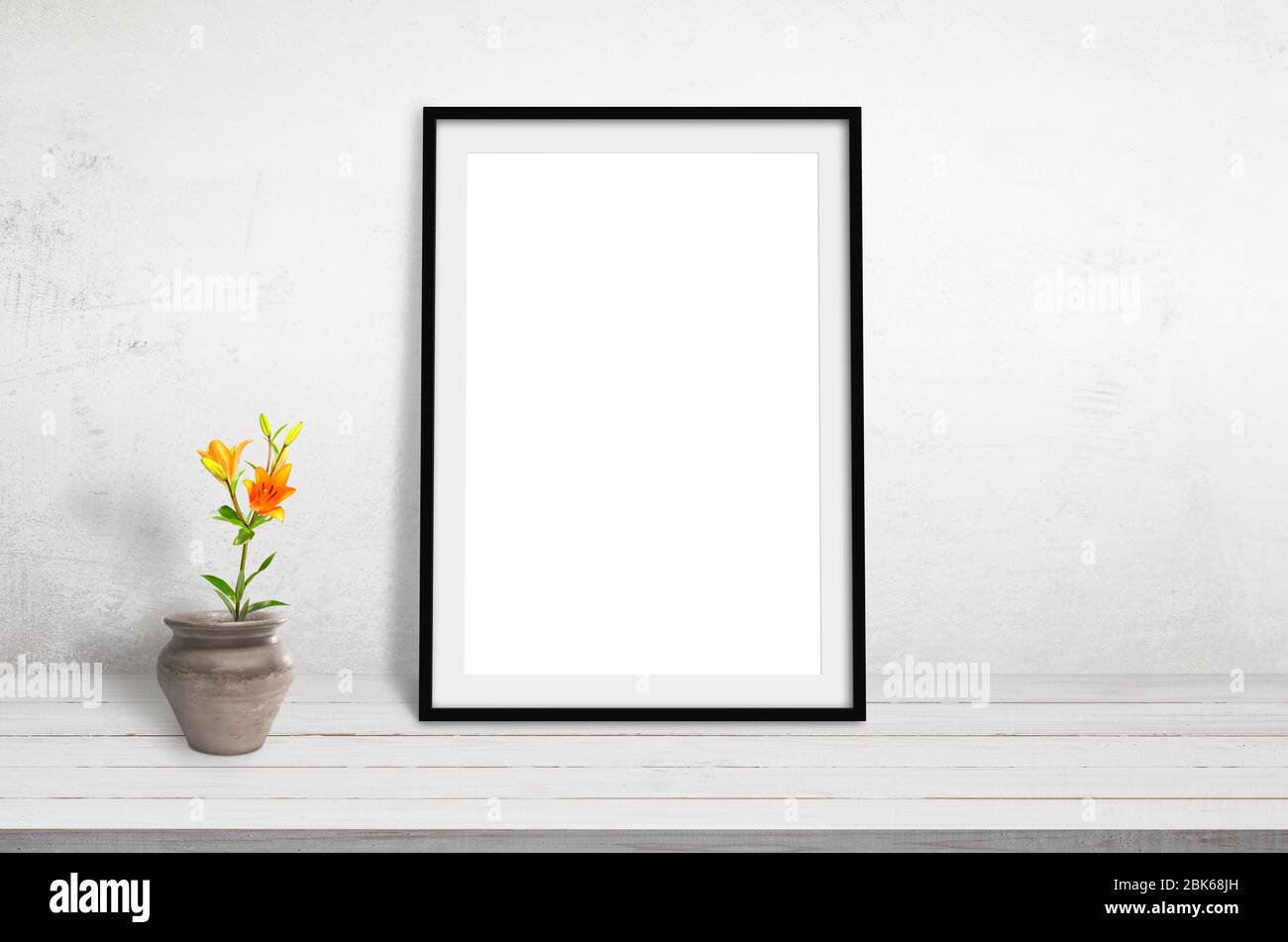Cadre photo s'emmoquant sur un bureau en bois blanc, incliné contre un mur. Plante et pot à côté Banque D'Images Cadre photo s'emmoquant sur un bureau en bois blanc, incliné contre un mur. Plante et pot à côté Banque D'Images
