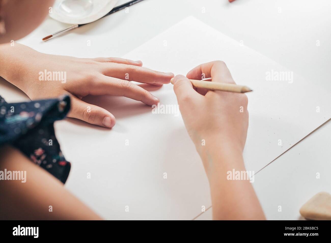 Les mains de fille s'esquissez au crayon sur une feuille de papier blanche. Passe-temps. Peinture Banque D'Images