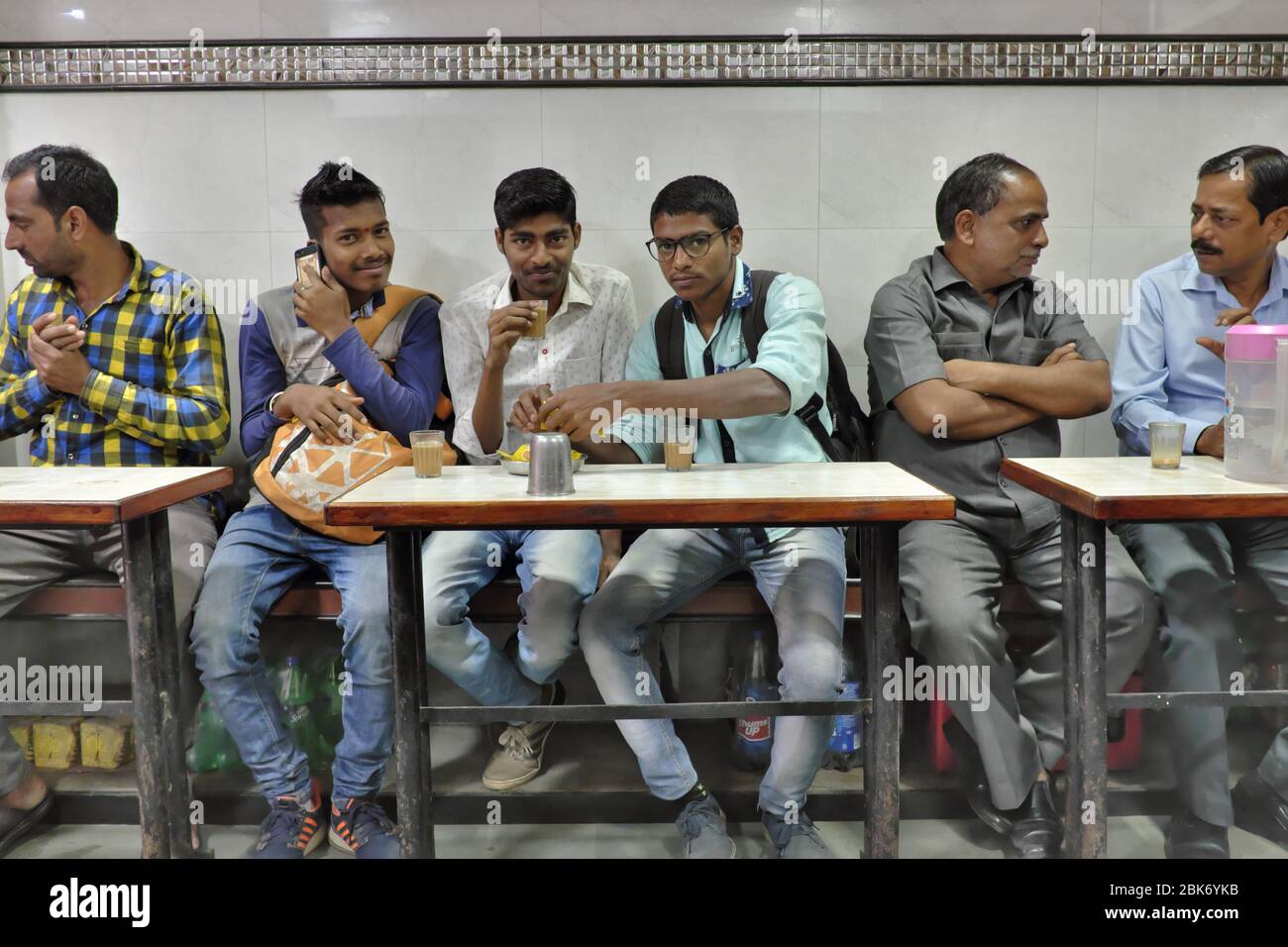 Clients dans une petite teashop (appelée local Chai ka Adda) dans la région de Kalbadevi, Bhuleshwar, Mumbai, Inde, en profitant d'une discussion sur le thé et le cookie Banque D'Images