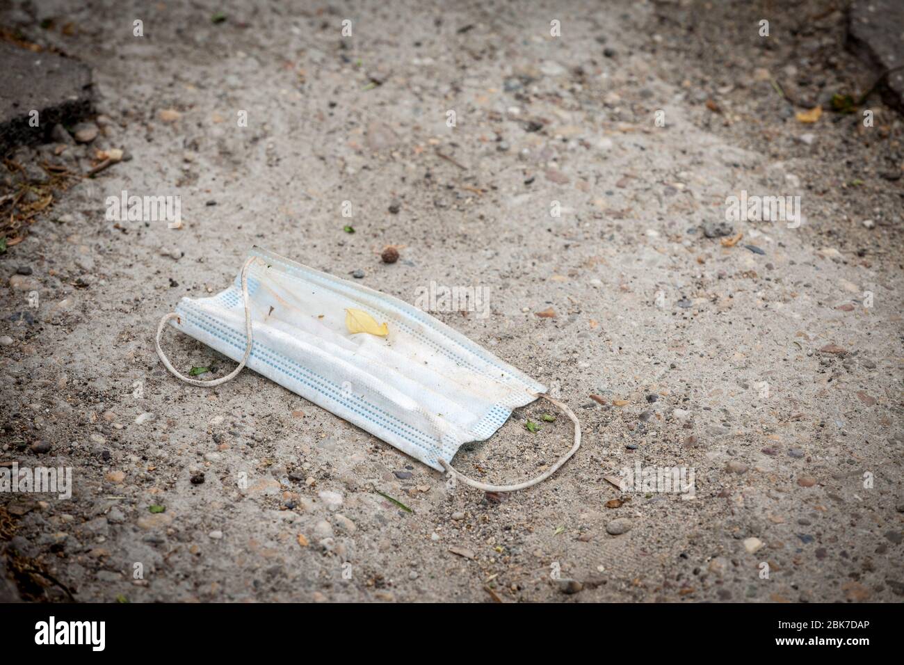 Masque facial utilisé, jetable, jeté sur le sol dans l'environnement comme ordures pendant la crise du covid 19 du corovavirus. Lancer un masque de protection utilisé Banque D'Images