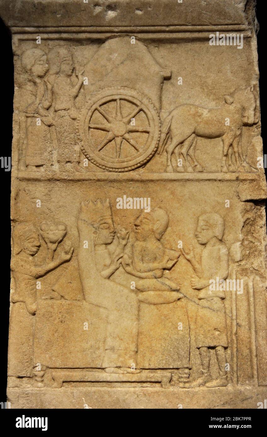 Stèle funéraire anatolienne-persane, 5 e siècle avant J.-C. Marble.de Daskylaion (Ergili, lac Manyas). Détail de la partie supérieure de la stèle représentant un cortege funéraire en deux scènes: Deux femmes pleurant se promenent derrière un chariot funéraire (scène supérieure). Une femme et un homme barbu s'assoient sur un canapé (scène inférieure). La main gauche de la femme tient un objet, tandis que sa main droite reçoit un œuf de l'homme. La table est flanquée de serviteurs ou d'esclaves. Sur la droite, l'esclave se tient devant un bateau placé sur un trépied. Sur la gauche, l'autre esclave porte un bol de fruits. Musée archéologique. Istanbul, Turquie. Banque D'Images