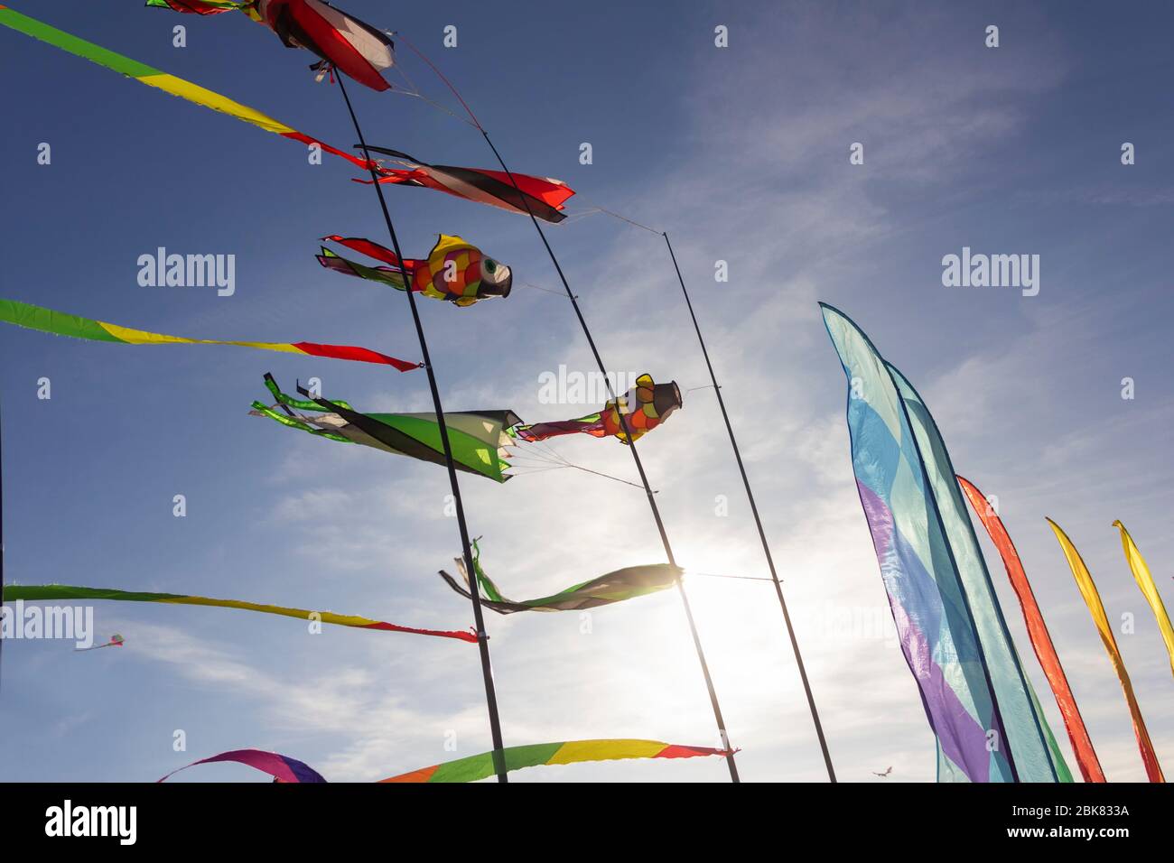 Rubans colorés et figurines en cerf-volant accrochés sur des poteaux et volantes sur fond bleu kite festival Banque D'Images