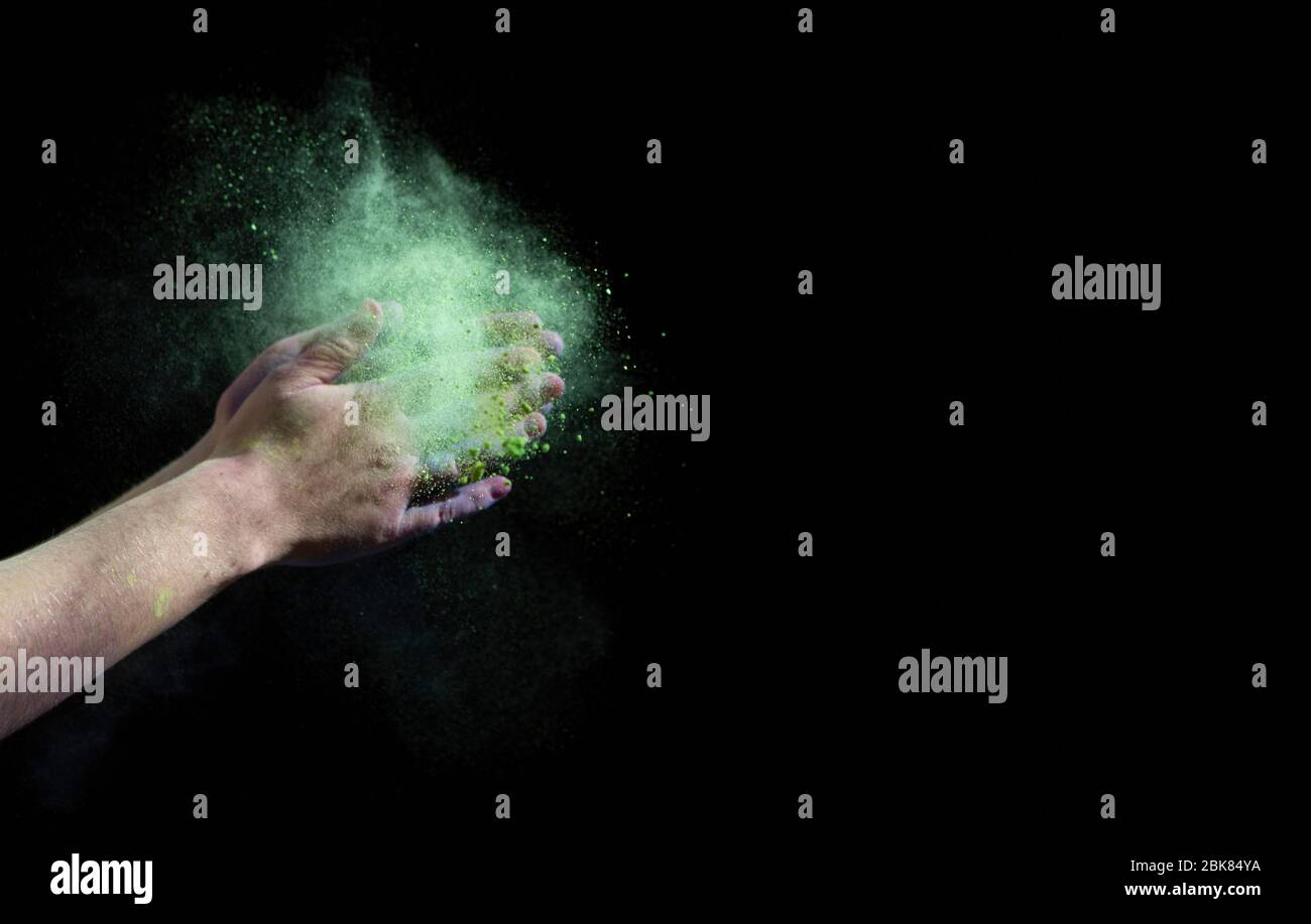 Nuage vert de peinture autour des mains sur fond noir Banque D'Images