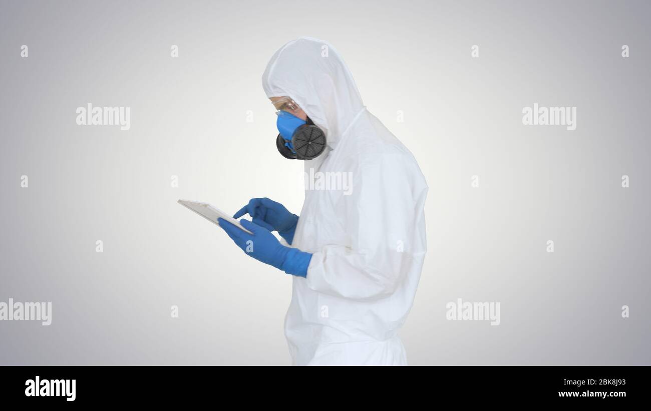 Un professionnel de santé portant un costume de noisette travaillant sur une tablette numérique sur fond dégradé. Banque D'Images