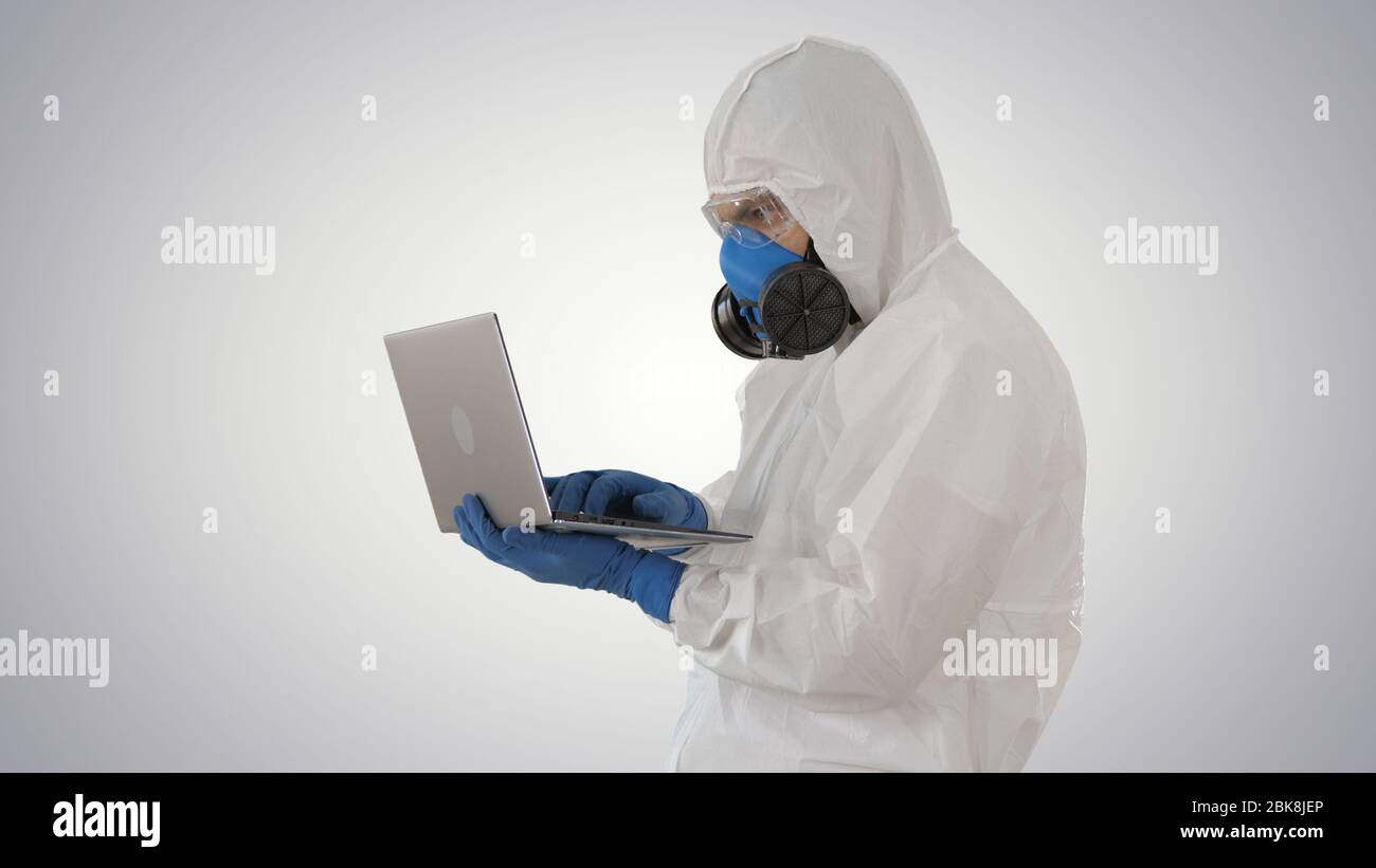 Médecin en uniforme de protection blanc utilisant un ordinateur portable sur fond dégradé. Banque D'Images