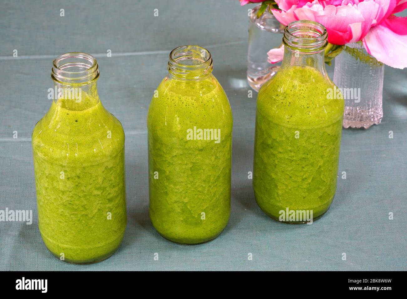Bouteilles en verre remplies de kale fraîche et de smoothie vert gingembre Banque D'Images