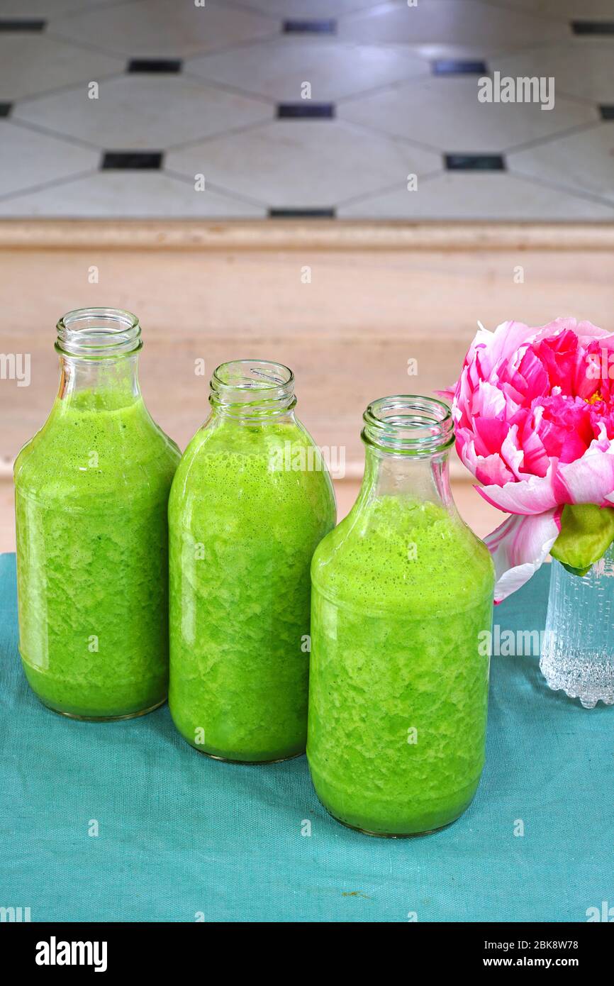 Bouteilles en verre remplies de kale fraîche et de smoothie vert gingembre Banque D'Images