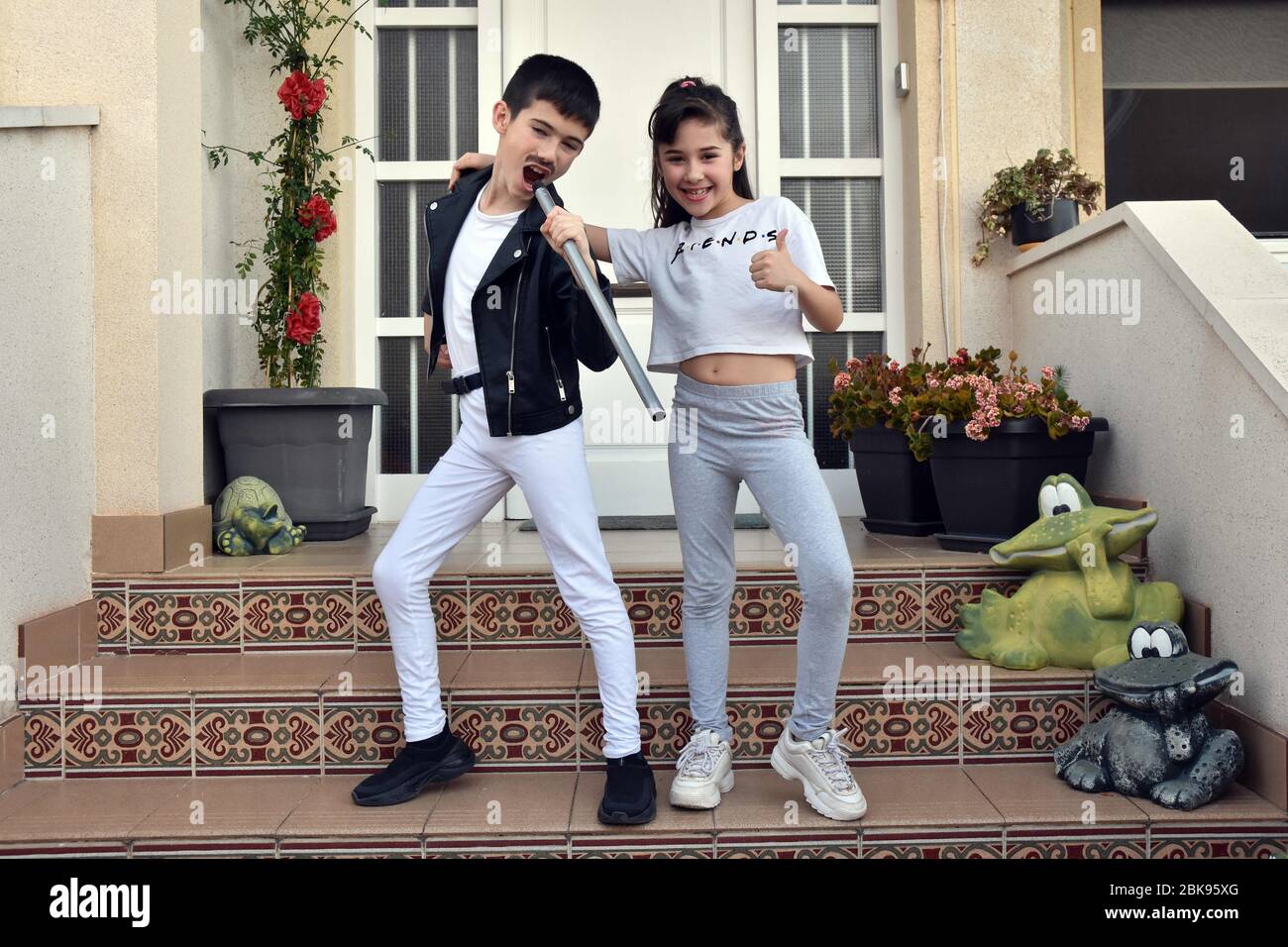 Vendrell, Espagne. 25 avril 2020. Un garçon vêtu comme la chanteuse de la Reine Freddy Mercury et sa sœur portant un T-shirt de la série télévisée Friends pose pour une photo sur la terrasse de leur maison pendant les années 80 spectacle de musique pour encourager leurs voisins pendant la séquestration.les résidents du Mas d'en Gual se présentent et applaudissent à 20 heures pour acclamer leurs voisins pendant la séquestration au milieu de la crise du coronavirus. Cette fois-ci, ils ont choisi le thème de la musique des années 80, un spectacle entier où ils ont pu voir épingler des filles artistes vêtus d'ABBA et un peu Freddy Mercure. (CRE Banque D'Images