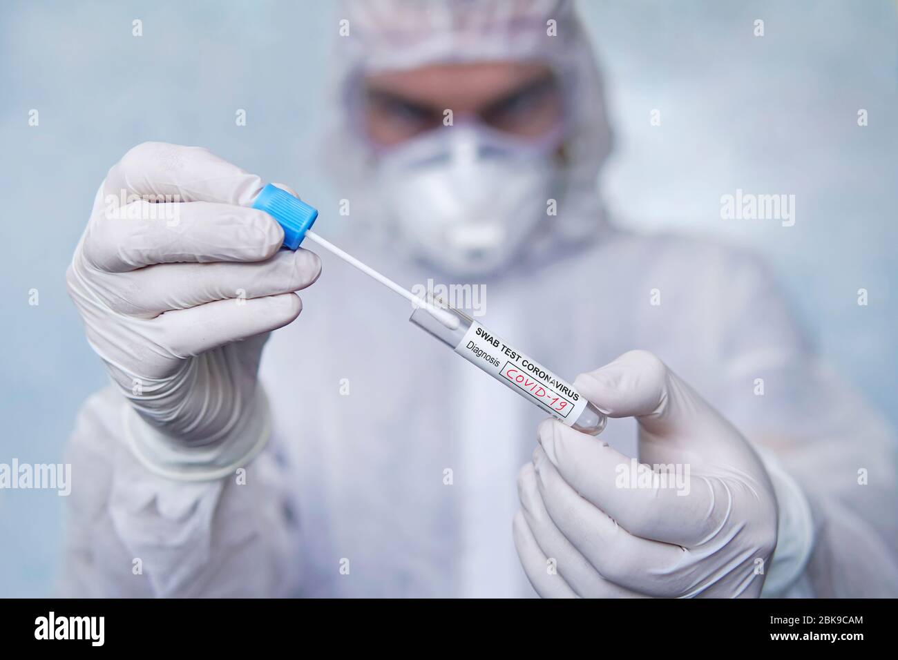 COVID-19. Écouvillon du coronavirus échantillon COVID-19. Test du coronavirus par écouvillon. Un homme en costume de protection chimique tient un tube à essai pour les analys Banque D'Images