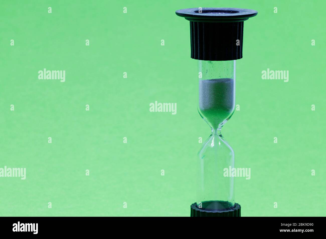 hourglass avec sable blanc sur fond vert Banque D'Images