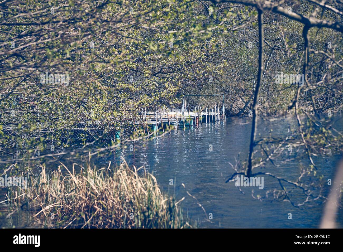 Quelques bateaux se trouvent sur une passerelle dans l'eau dans un lac tôt le matin dans une ambiance calme Banque D'Images