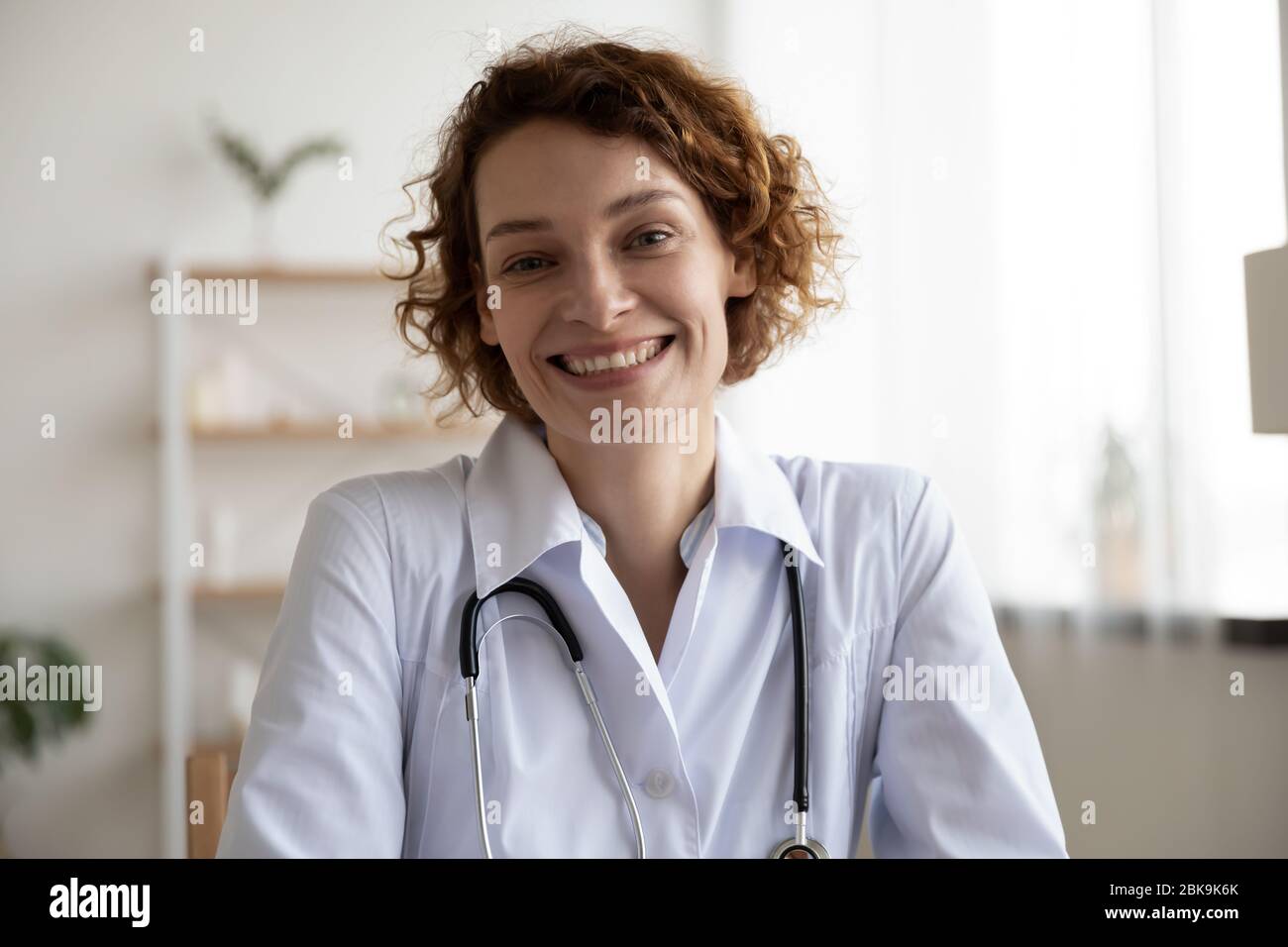Le médecin heureux porte un manteau médical blanc regardant l'appareil photo Banque D'Images