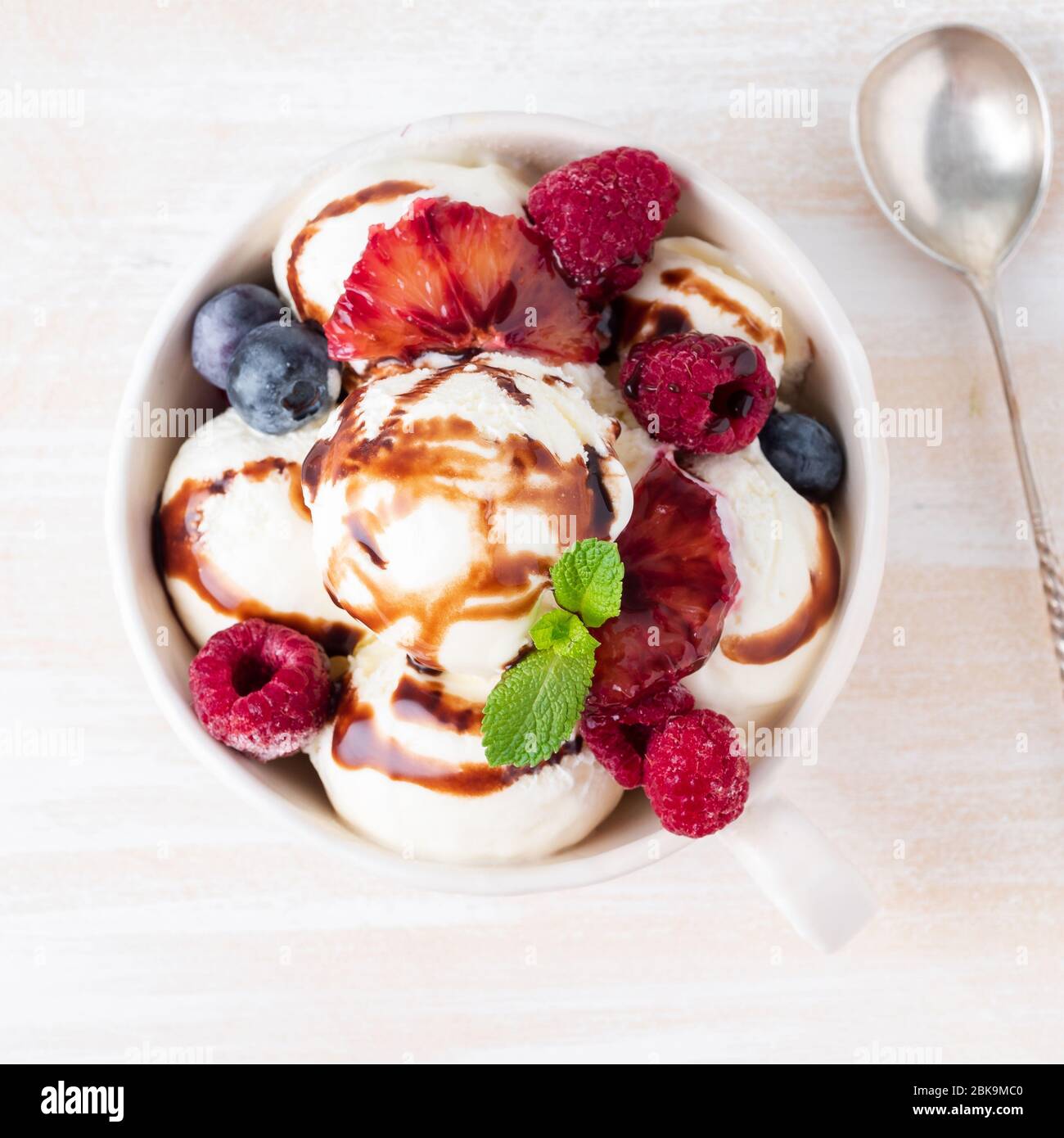 Boules de glace vanille dans un mug avec framboises et bleuets Banque D'Images