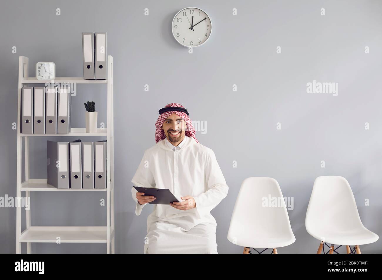 Un travailleur arabe attend un entretien avec un CV dans les mains assis sur une chaise dans le bureau. Banque D'Images