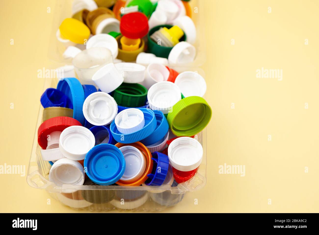 Triez les bouchons de bouteille en plastique. Recyclage. Aucun gaspillage. Arrière-plan jaune avec place pour le texte. Écologique. Protéger la nature de la pollution et des débris Banque D'Images