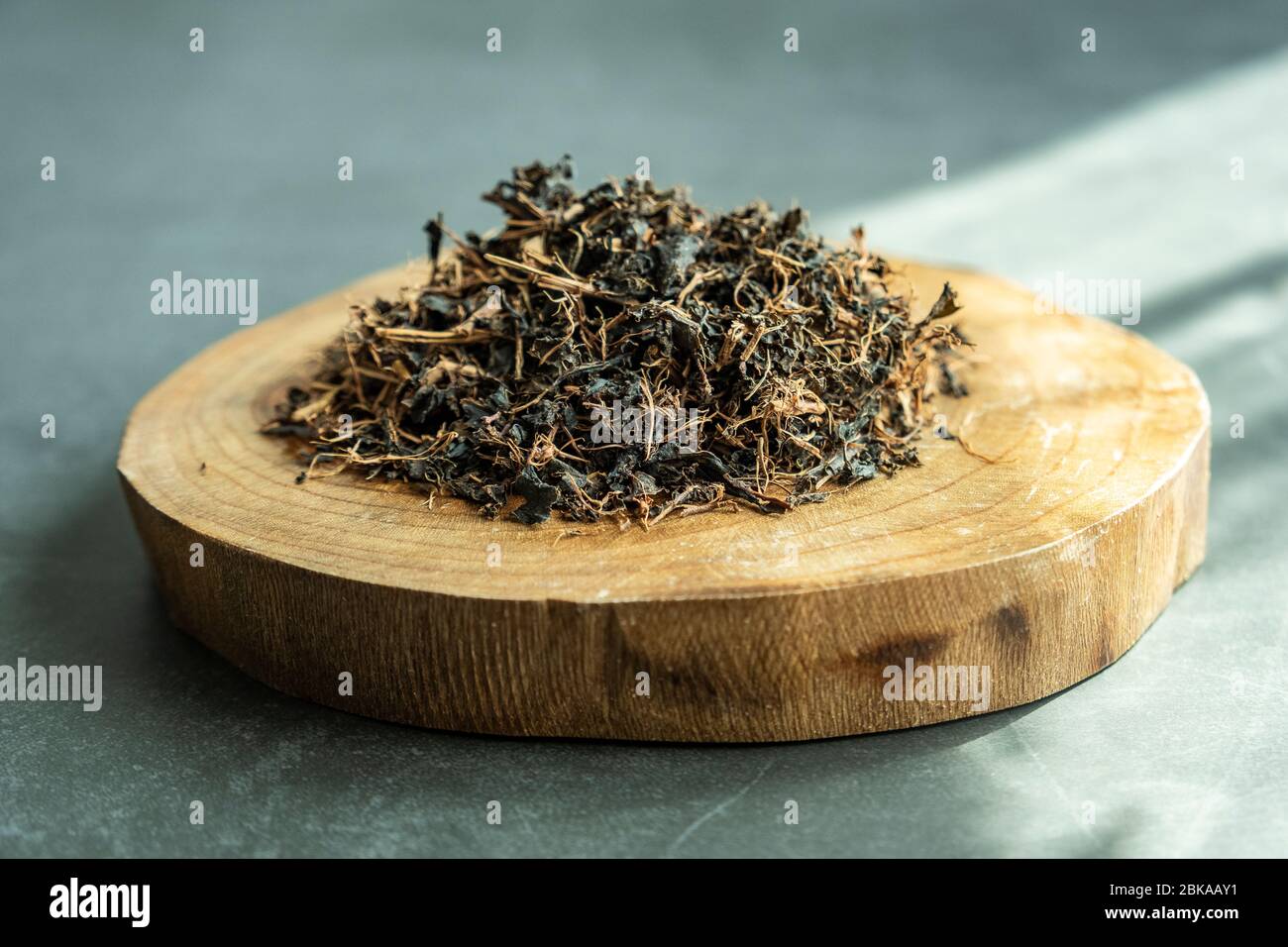 Feuille de thé noire sèche dans un plateau en bois sur fond de béton, pierre. Boisson traditionnelle, saine et biologique. Banque D'Images