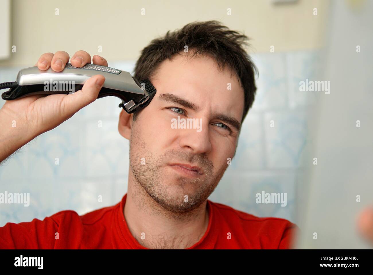 Un homme coupe ses cheveux sur la tête avec un rasoir électrique.  Nettoyez-vous seul. Vous souffrez de la tonte des cheveux Photo Stock -  Alamy